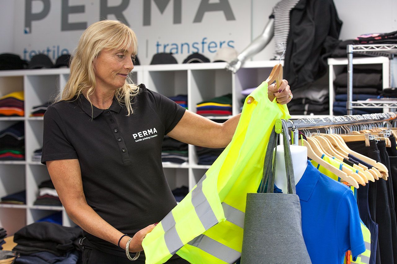 Eine Mitarbeiterin von Perma begutachtet bedruckte Kleidung